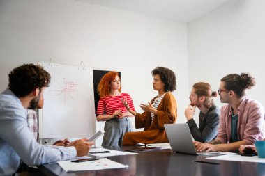 Çeşitli mutlu çalışanlar dijital cihazla raporları analiz ediyor, pazarlama, istatistiksel verileri tartışıyor, konuşuyor, beyin fırtınası yapıyor. İş toplantısı konsepti