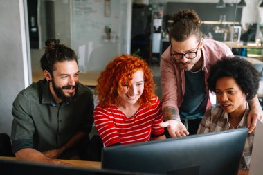 Mixed team of software engineers brainstorming ideas for new code library in front of computer screens compiling algorithms. Diverse app developers collaborating on group project in it agency office.