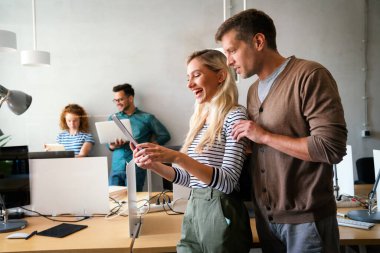 Yönetim kurulunda dikilirken dijital tablet kullanan iki genç iş adamı. İki iş arkadaşı toplantı sırasında tartışıyorlar. Çeşitli iş adamları takım olarak çalışıyor..