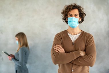 Karışık ırklar erkek ve iş stili olan insanlar ve tıbbi maskeler aletlerle ayakta duruyor ve sosyal mesafeyi koruyorlar. Koronavirüs salgını