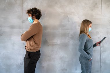 İşteki sosyal izolasyon, üniversite. Genç iş adamları, ofiste maskeli öğrenciler sosyal mesafeyle çalışmaya çalışıyor.