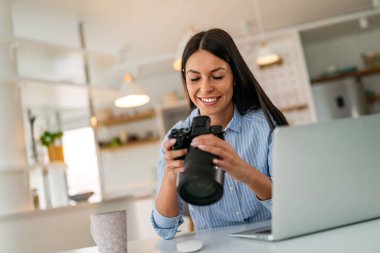 Ofiste çalışan fotoğraf makineli dizüstü bilgisayarı olan yaratıcı bir kadın. İş adamları online pazarlama yapıyor. Başarılı bağımsız yaratıcı sanatçı kız işi..