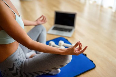 Evde spor yapmak, internetten video izlemek, dizüstü bilgisayarla çalışmak. Sağlıklı kalmak için spor yapan mutlu zinde bir kadın..