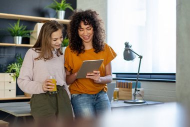 Modern aletleri ve dizüstü bilgisayarı olan bir grup genç evde birlikte ders çalışıp eğleniyorlar.