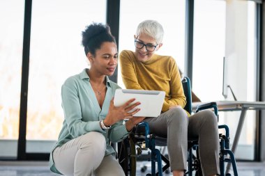 Modern bir çalışma alanında işbirliği yapan, çizelgeleri analiz eden ve birlikte çalışan çok ırklı iş arkadaşları, takım çalışmalarını, çeşitliliği ve dahil edilmeyi gösteriyor