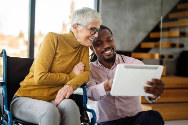Nesiller arası profesyonellerden oluşan bir grup bir iş toplantısı yapıyor. Tekerlekli sandalye kullanan ve modern bir ofiste takım çalışmasını tasvir eden birini içeriyor.