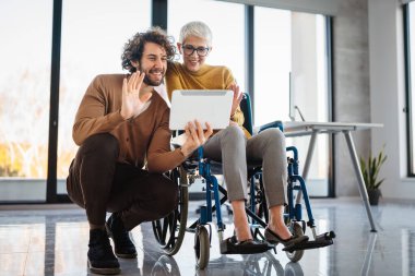 Çeşitli iş arkadaşları iş birliği yapıyor. Tekerlekli sandalyedeki kadın çalışıyor, takım çalışması. Modern, açık planlı çalışma alanında önemli bir şey tartışıyoruz.