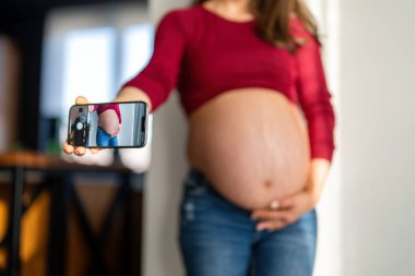 Hamilelik karnına yakın çekim. Hamile kadın evde dinleniyor. Cilt bakımı, sağlık, yaşam tarzı için karın bekliyor.