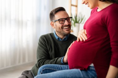 Aşk, şefkat, ilişki ve yeni aile kavramı. Aşık bir adam hamile karısına sarılır, birlikte bebeklerin gelmesini beklerler.