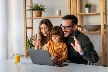 Çocuklu mutlu bir aile birlikte dizüstü bilgisayar kullanarak eğleniyor, ebeveynler ve çocuklar evde gülüyor bilgisayarla eğleniyor, komik internet videoları izliyor, online arama yapıyor.
