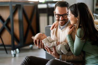 Gülümseyen anne ve baba yeni doğan kızlarını kucağında tutuyorlar. Aile ebeveynliği kavramını seviyorum.