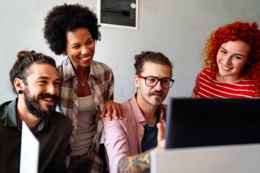 Mixed team of software engineers brainstorming ideas for new code library in front of computer screens compiling algorithms. Diverse app developers collaborating on group project in it agency office.