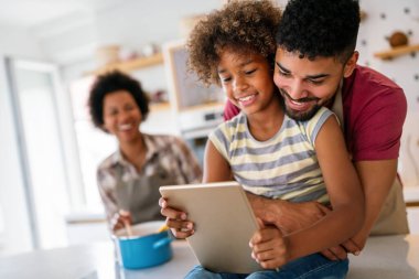 Mutlu Afrikalı aile evde cihazla eğleniyor, siyahi ebeveynler ve çocuk dijital tablet kullanıyorlar ve birlikte ekrana bakıyorlar.