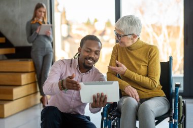 Tekerlekli sandalyedeki kadına yardım etmek, modern ofiste sohbet etmek. Takım çalışması, işyeri, iş dünyası, çeşitlilik, işbirliği, destek