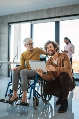 A bright, contemporary office space with a diverse group of professionals working together. Includes a person using a wheelchair, promoting inclusivity. clipart