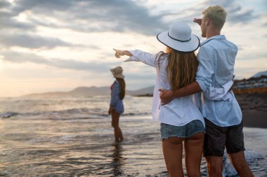 Genç bir çift gülümseyerek denizde yürüyor ve yaz tatilinin tadını çıkarıyor, birlikte seyahat ediyorlar. Yeni tatiller ve çiftler konsepti.