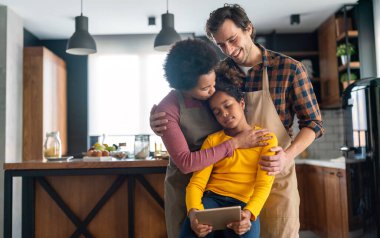 Çok mutlu, çoklu etnik kökenli genç bir aile. Kızları mutfakta eğleniyor. Mutlu ebeveynler hafta sonunun keyfini çıkarıyor..