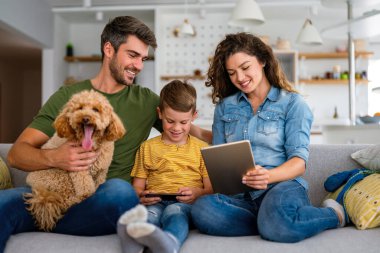 Mutlu aile, çocuklu ebeveynler başvuru ile eğleniyor, video karikatür izliyor ya da evde birlikte oyun oynuyorlar..