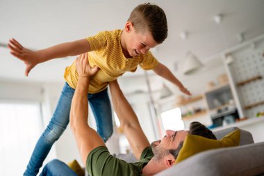 Ebeveyn ve çocuk arkadaş oluyor. Neşeli baba ve oğul, eğlenceli, neşeli genç baba kanepede uzanıyor, heyecanlı küçük oğlunu kaldırıyor, evde birlikte vakit geçiriyorlar. Bekar baba kavramı