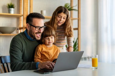 Çocuklu mutlu bir aile birlikte dizüstü bilgisayar kullanarak eğleniyor, ebeveynler ve çocuklar evde gülüyor bilgisayarla eğleniyor, komik internet videoları izliyor, online arama yapıyor.