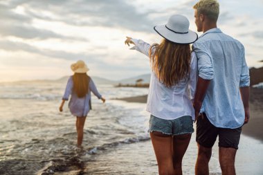 Genç bir çift gülümseyerek denizde yürüyor ve yaz tatilinin tadını çıkarıyor, birlikte seyahat ediyorlar. Yeni tatiller ve çiftler konsepti.