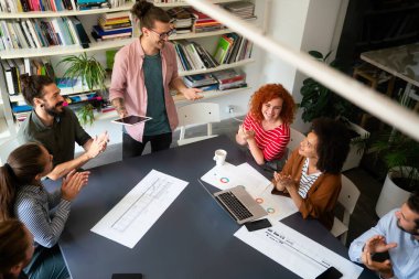 Mutlu iş arkadaşları, modern ofisteki iş arkadaşlarıyla iş başında ve toplantıdalar. Proje fikirlerini tartışmak veya strateji geliştirmek.