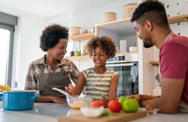 Mutlu Afro-Amerikan ailesi mutfakta eğleniyor ve birlikte yemek pişiriyor. Evde sağlıklı yiyecekler..