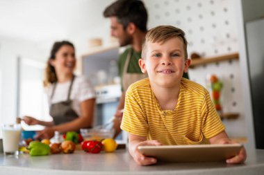 Çocuklu mutlu bir aile tablet bilgisayar kullanarak eğleniyor, ebeveynler ve çocuklar gülüyor evde bilgisayarla komik internet videoları izleyip, online arama yapıyorlar.