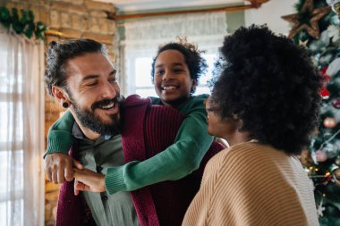 Mutlu çokkültürlü ebeveynler kızlarıyla eğleniyor, birbirlerine sarılıyorlar, anne ve baba gülüyor, kucaklaşıyorlar. Evde aile hayatı oyunlarının tadını çıkarıyorum.