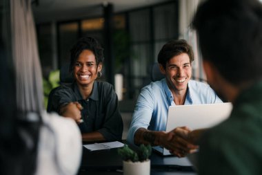 Ofiste dijital tablet kullanarak çalışan bir grup mutlu ve çeşitli profesyonel iş adamları. Çok ırklı bir genç girişim ekibi bir proje üzerinde çalışıyor.