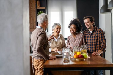 Çoklu nesil çok ırklı aile eğleniyor, neşeli bir mutfak masasının etrafında konuşuyorlar. Aile mutluluğu kavramı.