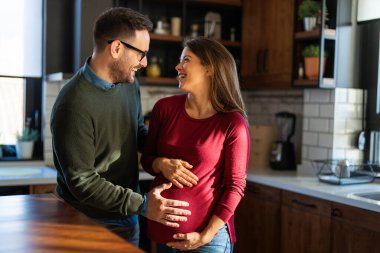 Aşk, şefkat, ilişki ve yeni aile kavramı. Aşık bir adam hamile karısına sarılır, birlikte bebeklerin gelmesini beklerler.