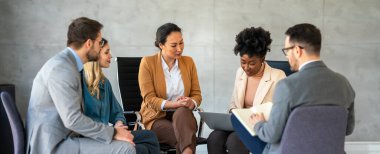 İş toplantısında ya da grup terapisinde tartışan insanlar. Meslektaşlarından oluşan bir ekip ofiste oturup tecrübeli koçun tavsiyelerini ve uzmanlığını paylaşıyor.