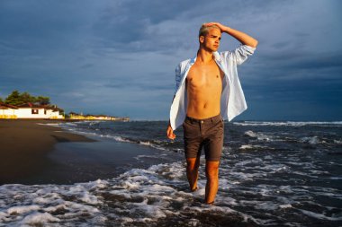 Tropik bir plajda gülümseyen adam, tatilinin tadını çıkarıyor. Bayram seyahatleri ve tropikal plaj maceraları için mükemmel.