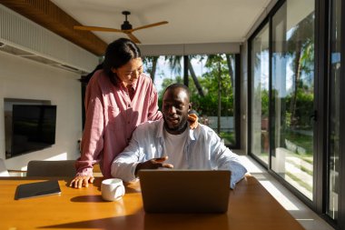 Genç ve çok ırklı çift evde bilgisayar ve dijital cihaz kullanırken eğleniyor. İnsanlar, teknoloji, online yaşam tarzı konsepti