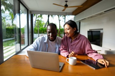 Uzaktan çalışan çok kültürlü bir çift, çevrimiçi finans ve yatırım planlıyorlar. Dijital göçebe yaşam tarzı, takım çalışması ve her yerden gelen akıllı finansal kararlar.