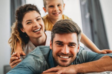 Üç kişilik bir aile evde neşeyle vakit geçirir. Çocukların iyi ruh hali ailelere zevk verir..