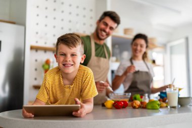 Mutlu aile, çocuklu ebeveynler başvuru ile eğleniyor, video karikatür izliyor ya da evde birlikte oyun oynuyorlar..