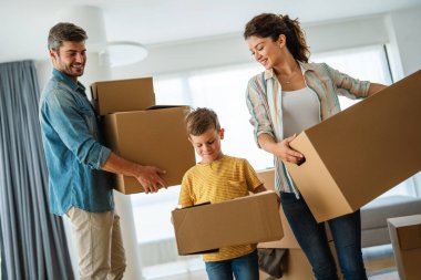 Yeni bir apartmanda kutularla taşınan çocuklu mutlu bir aile. Ev sahibi, taşınma günü için heyecanlı aile, taşınma ve kiralama konsepti