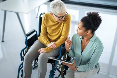 Nesiller arası profesyonellerden oluşan bir grup bir iş toplantısı yapıyor. Tekerlekli sandalye kullanan ve modern bir ofiste takım çalışmasını tasvir eden birini içeriyor.