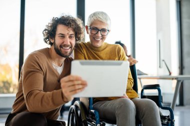 Tekerlekli sandalyedeki kadına yardım etmek, modern ofiste sohbet etmek. Takım çalışması, işyeri, iş dünyası, çeşitlilik, işbirliği, destek