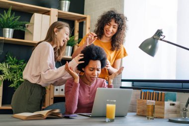 Çalışan siyahi anne bilgisayar kullanıyor ve çocukları onu rahatsız ederken işine odaklanmaya çalışıyor.