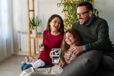 Sevgi dolu koca ve çocuklar hamile annelere sarılıyorlar, karnına dokunuyorlar. Mutlu, heyecanlı bir aile bebek bekliyor, yeni aile üyeleri.