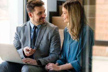 Ofiste yeni bir proje üzerinde çalışırken gülen iş adamları. Modern bir çalışma alanında çalışırken bilgisayar kullanan bir grup farklı iş adamı..