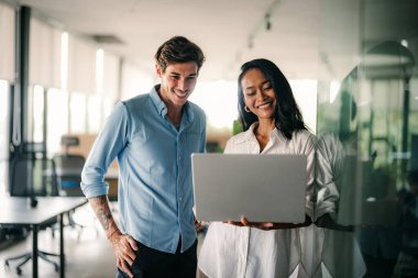 Mixed team of software engineers brainstorming ideas for new code library in front of computer screens compiling algorithms. Diverse app developers collaborating on group project in it agency office.