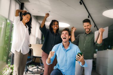 Coşkulu, çeşitli, etnik çeşitlilikte genç meslektaşlar ortak kurumsal başarıyı ya da hedef başarısını kutluyor, modern ofiste kaygısız parti zamanlarının tadını çıkarıyor.