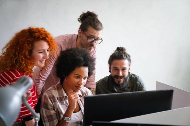 Mixed team of software engineers brainstorming ideas for new code library in front of computer screens compiling algorithms. Diverse app developers collaborating on group project in it agency office.