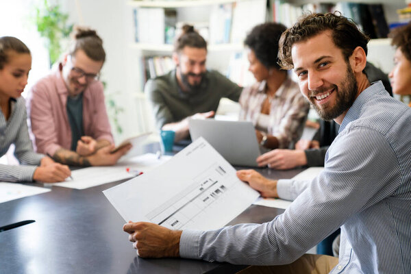 Diverse group of happy employees analyzing reports with digital device working together, discussing marketing, statistic data, talking, brainstorming. Business meeting concept