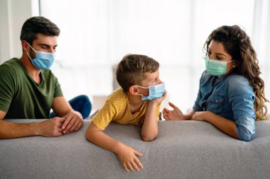 Aile, koronavirüse karşı maske takıyor, kirlilik, hastalık ve evde kalıyor. Virüsü, gribi ve kirliliği önlemek için koruyucu maske takan üzgün aile.