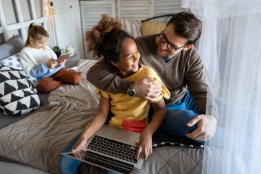 Bekar baba, evdeki dijital tabletle oturma odasındaki yatakta etnik çeşitlilikteki çocuğuyla oynuyor.